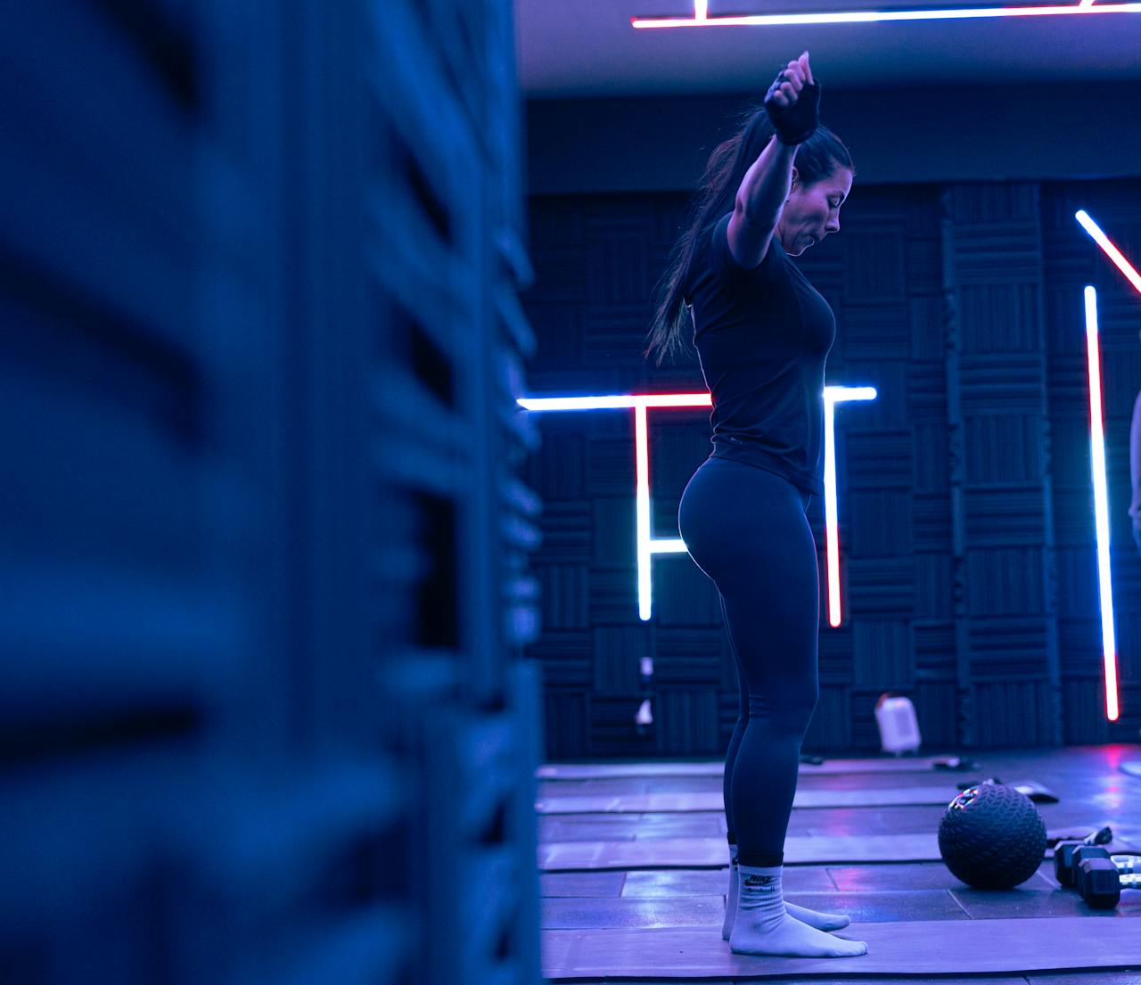 Fitness enthusiast exercising in a stylish neon-lit studio, embodying strength and focus.
